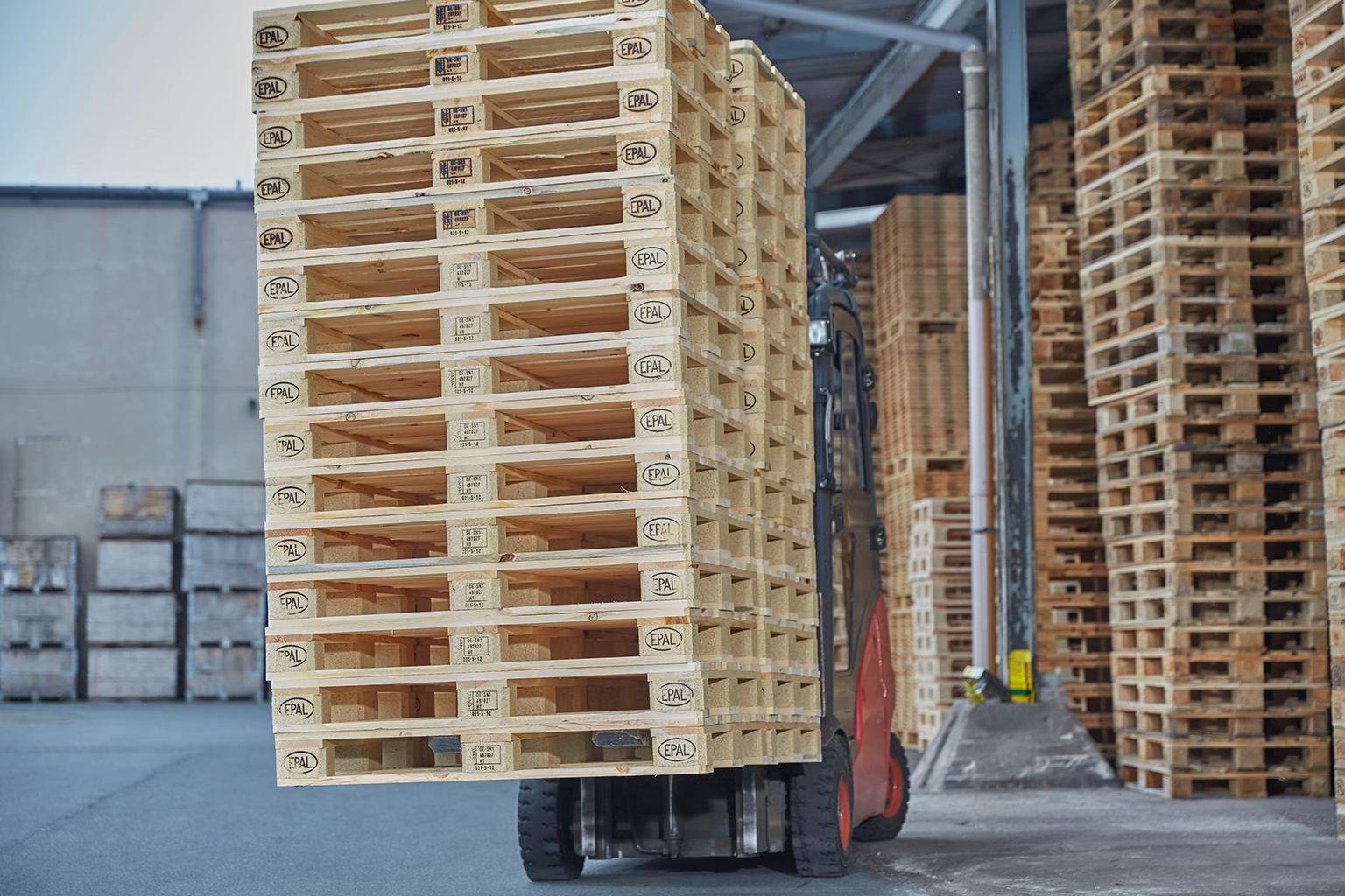 Forklift carrying a stack of wooden pallets